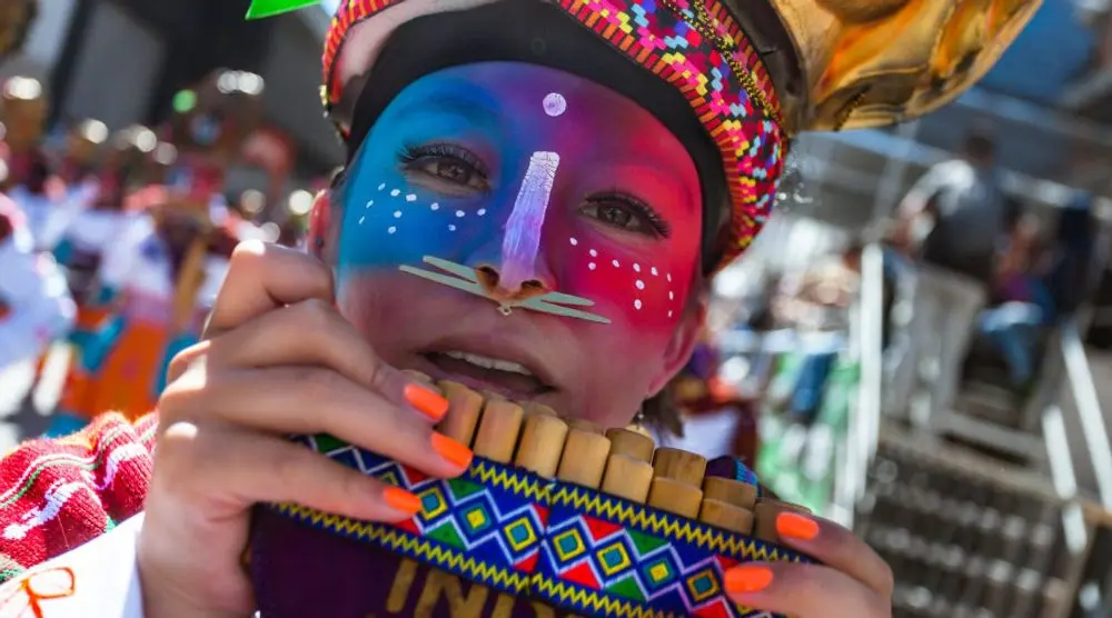 Performer with a painted face playing pan pipes