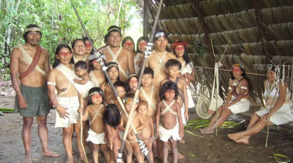 Indigenous family group outside a thatched shelter