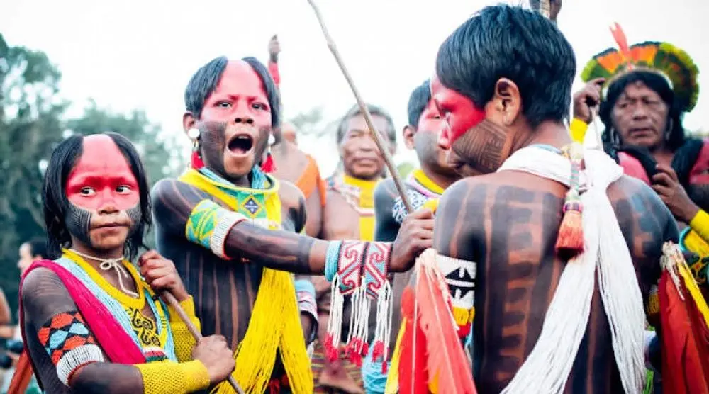 Indigenous people with red face paint and feathers