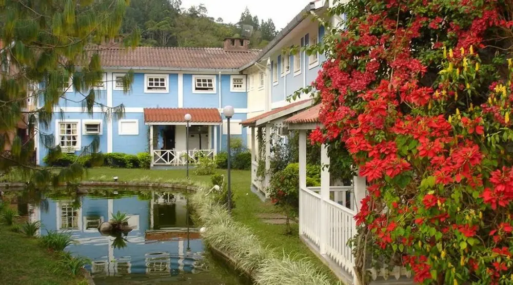 Blue house with flowers by a pond in Penedo