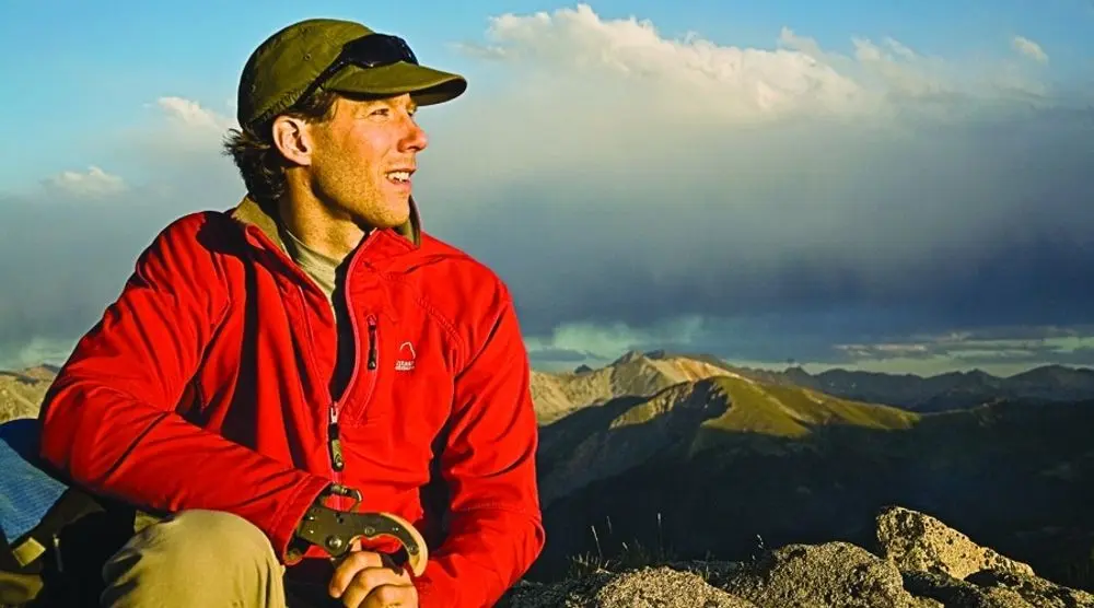 Hiker in a red jacket on a mountain at sunrise