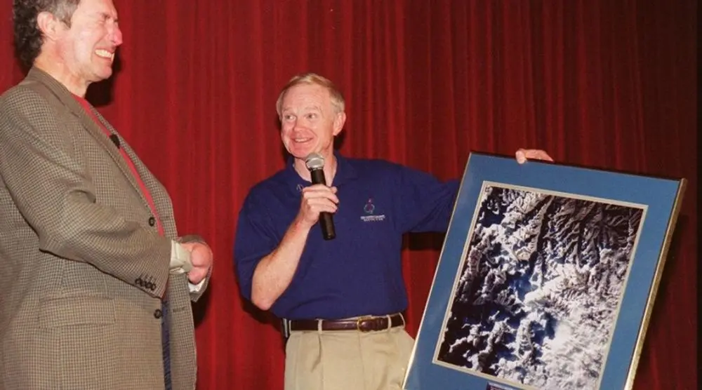 Man on stage presenting a framed photograph