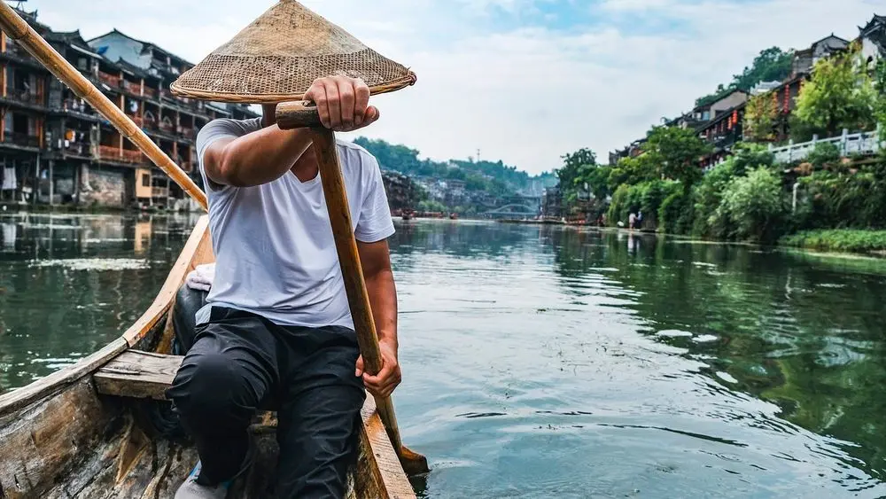 Boatman poling along a river in an old Chinese town