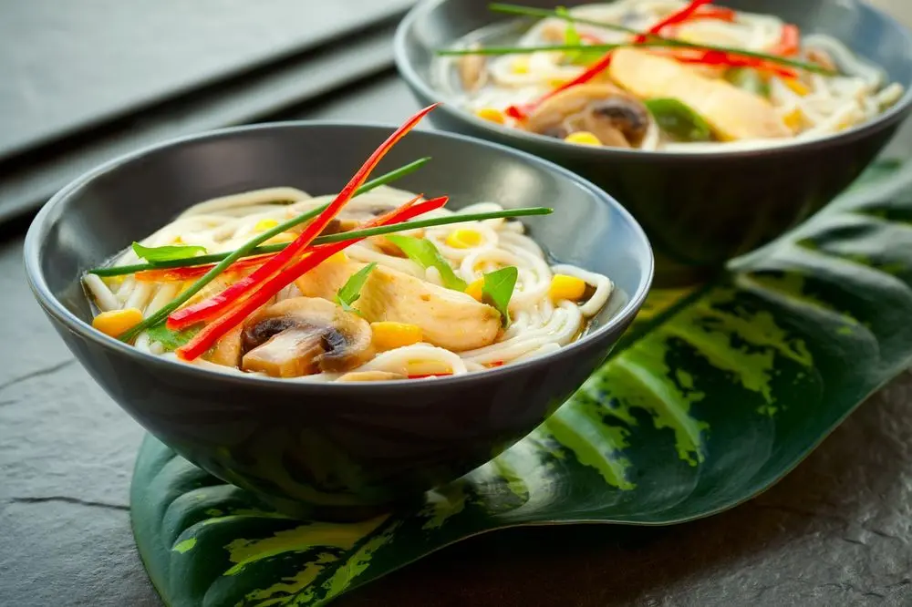 Bowls of noodle soup with chilli and herbs