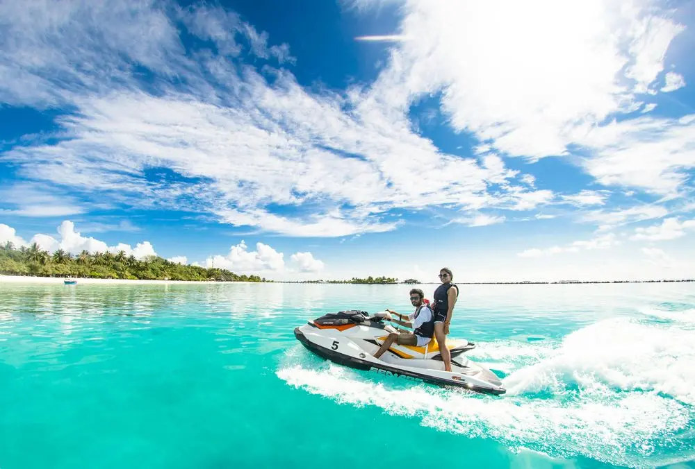 Couple riding a jet ski across a turquoise lagoon