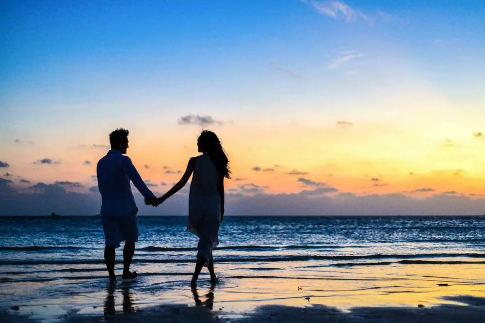 Couple holding hands on the beach at sunset