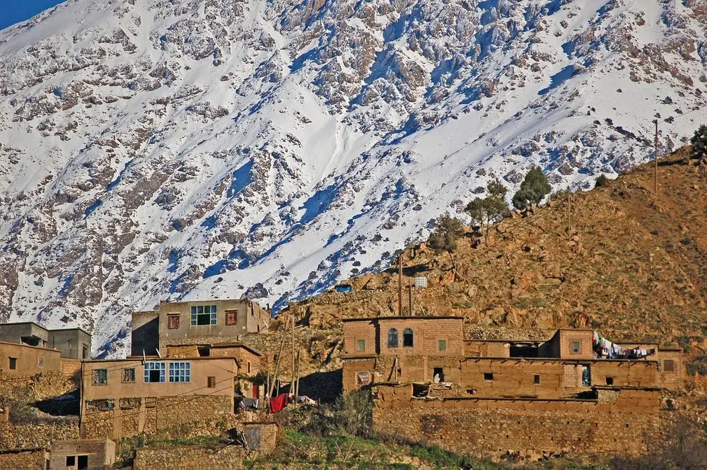 Mud-brick village below snowy Atlas slopes
