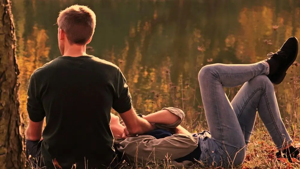Couple relaxing in a meadow at sunset