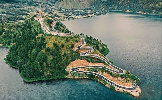 Winding road on a forested peninsula above a lake in Sumatra