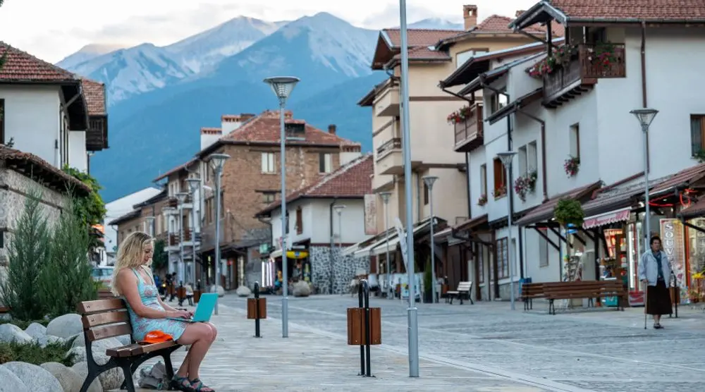 People relaxing on a town square below mountains