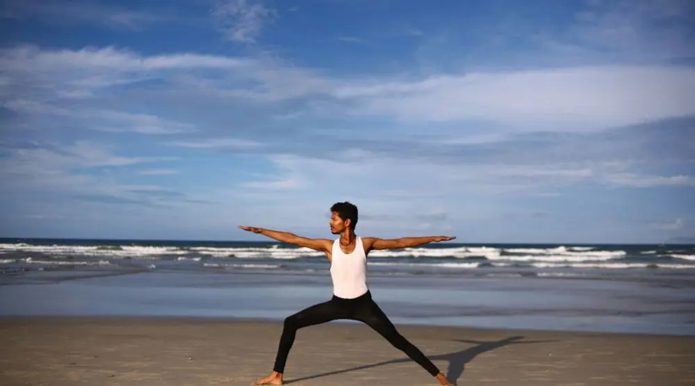 Man in warrior pose on a beach
