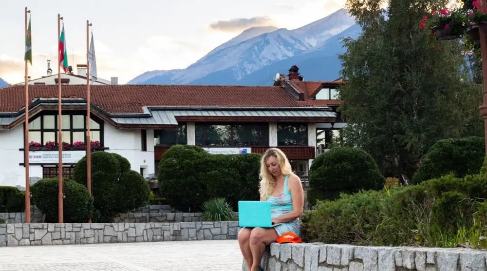 Woman working on a laptop outside a mountain hotel