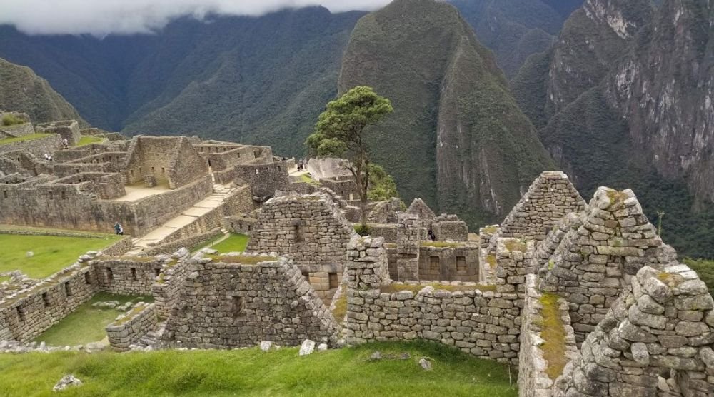 Machu Picchu ruins below green peaks
