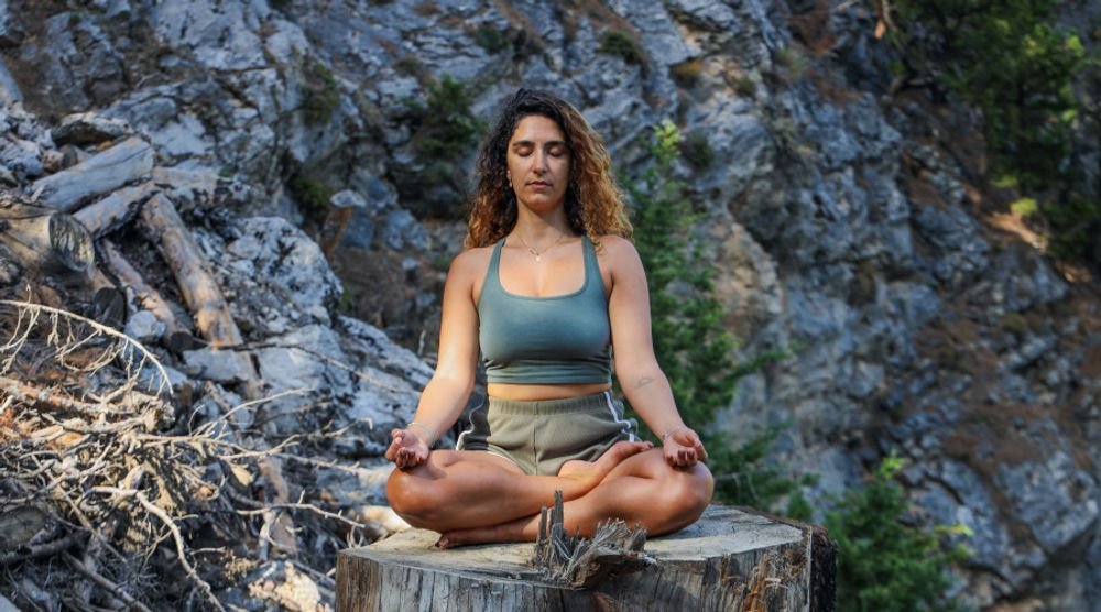 Woman meditating on a rock outdoors