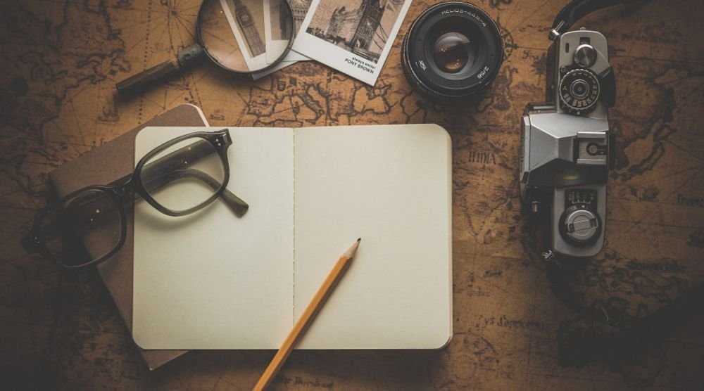 Notebook, glasses and vintage camera on a map