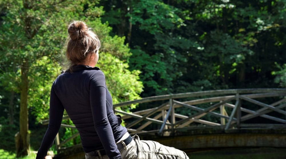 Woman resting by a footbridge in a forest