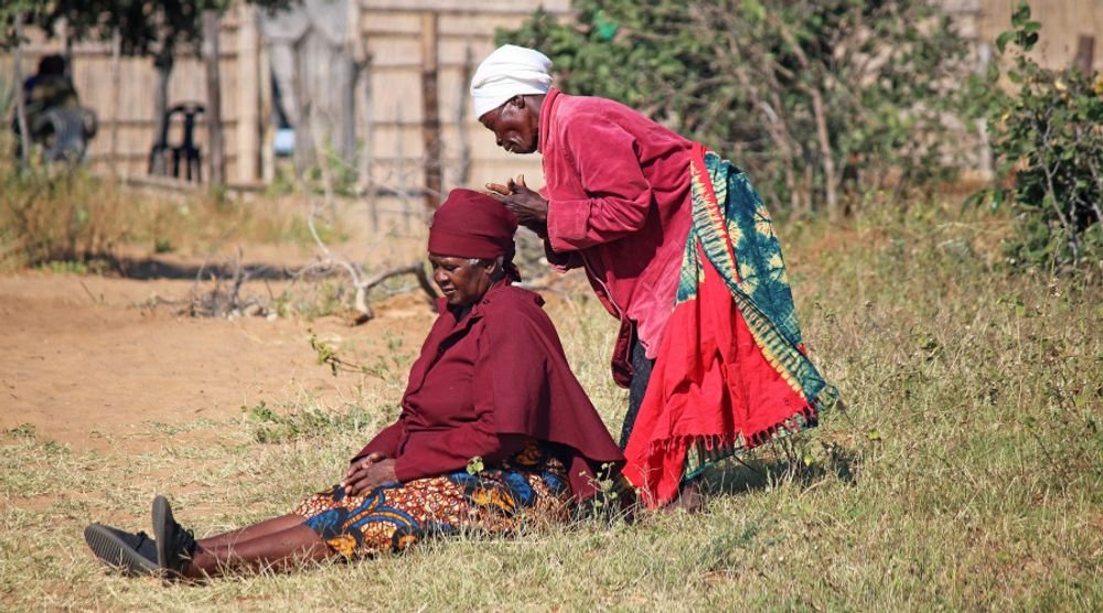 Two women in red shawls sitting together in a village