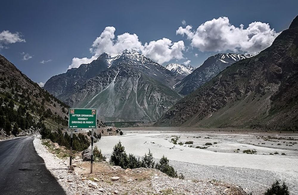 Road through a river valley below snowy peaks