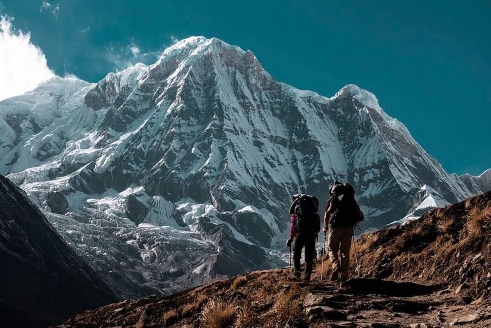 Trekkers below a snow-covered peak